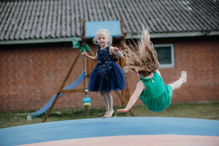 girl in blue dress playing on blue trampoline