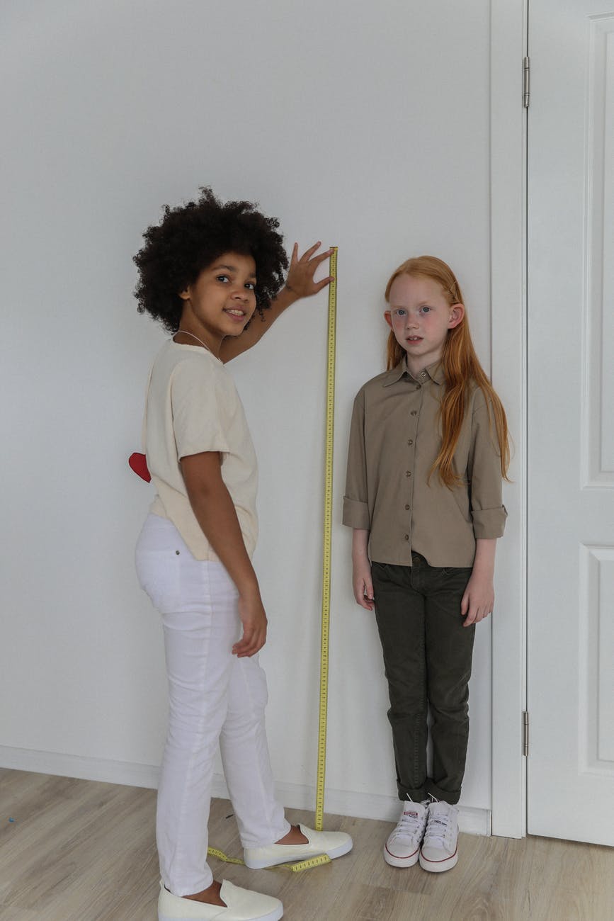 cheerful multiracial girls measuring each other